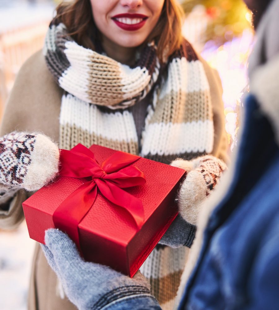 Cheerful woman getting gift from boyfriend at Christmas